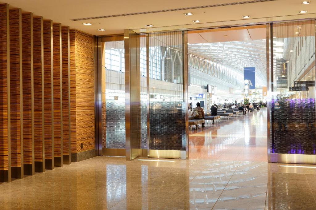 a lobby of a shopping mall with people sitting on benches at Haneda Excel Hotel Tokyu Haneda Airport Terminal 2 in Tokyo