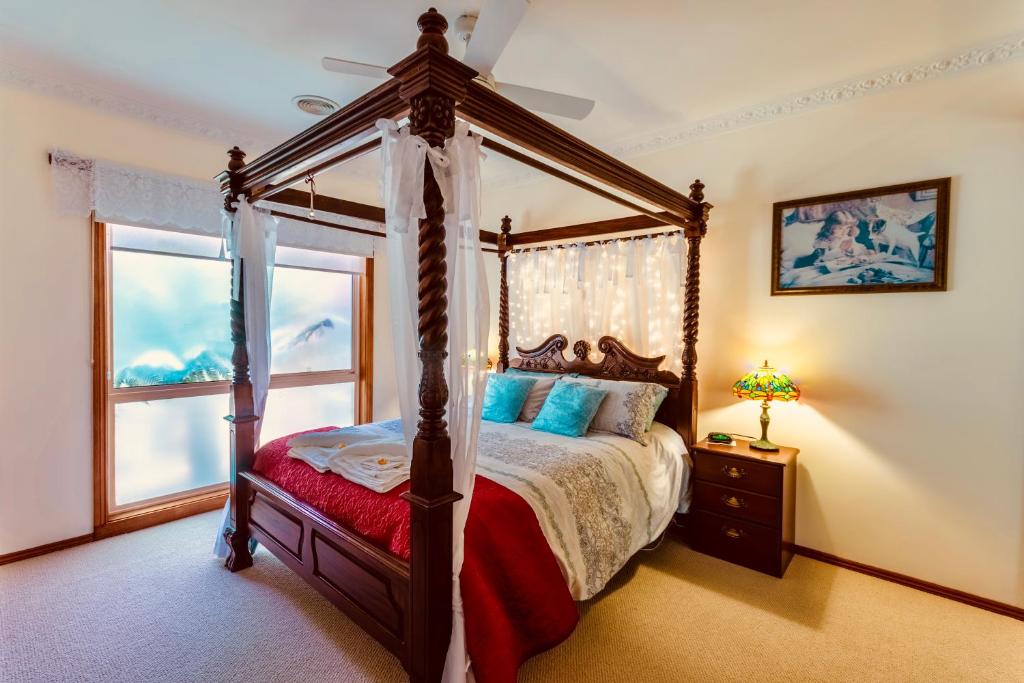 a bedroom with a canopy bed and a window at Fairy Wren Cottage Country to Coast Retreat in Wallington