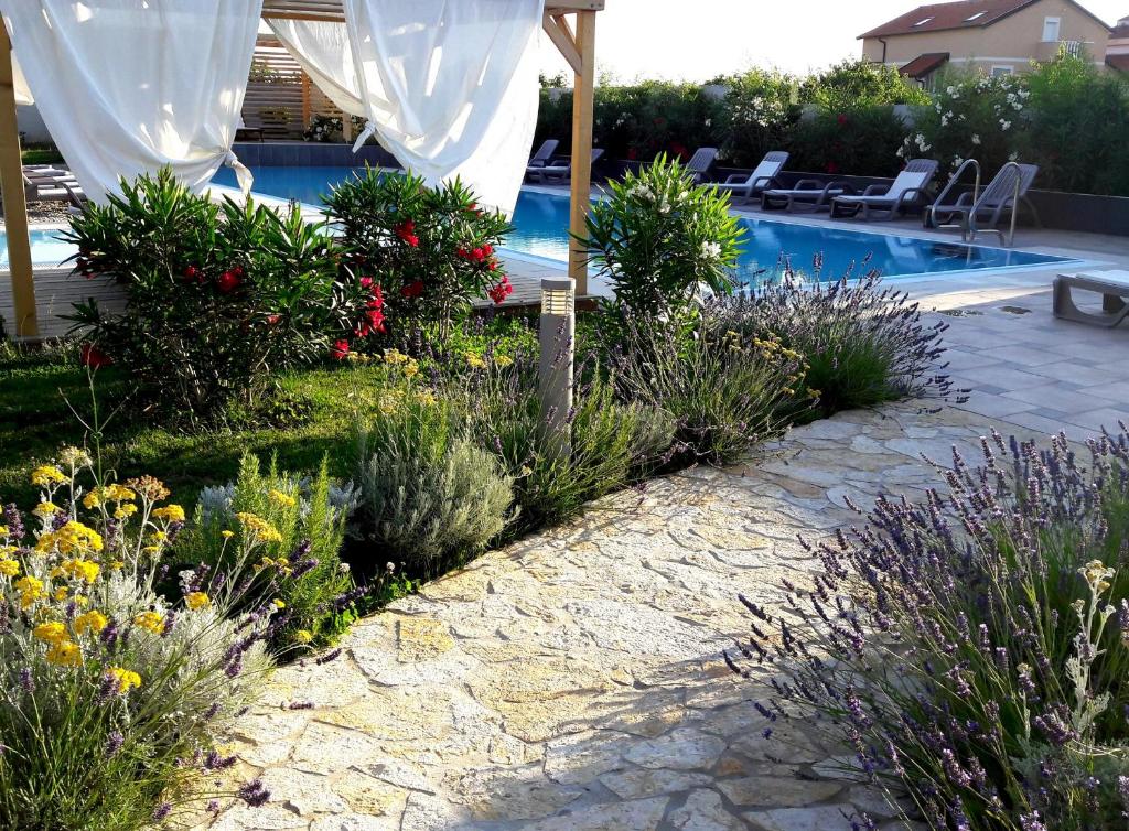 a garden with flowers and a swimming pool at My Nest Accommodation in Privlaka
