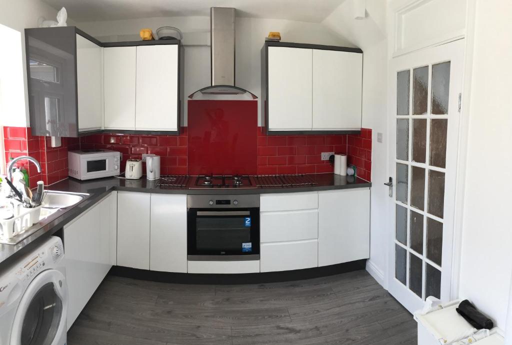 a kitchen with white cabinets and a red brick wall at Rushden Vacation Home in Hendon