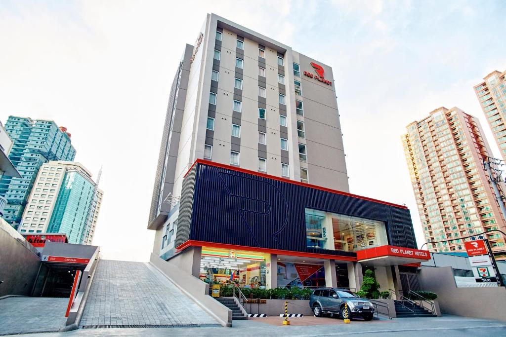 un bâtiment avec une voiture garée devant lui dans l'établissement Red Planet Makati Amorsolo, à Manille