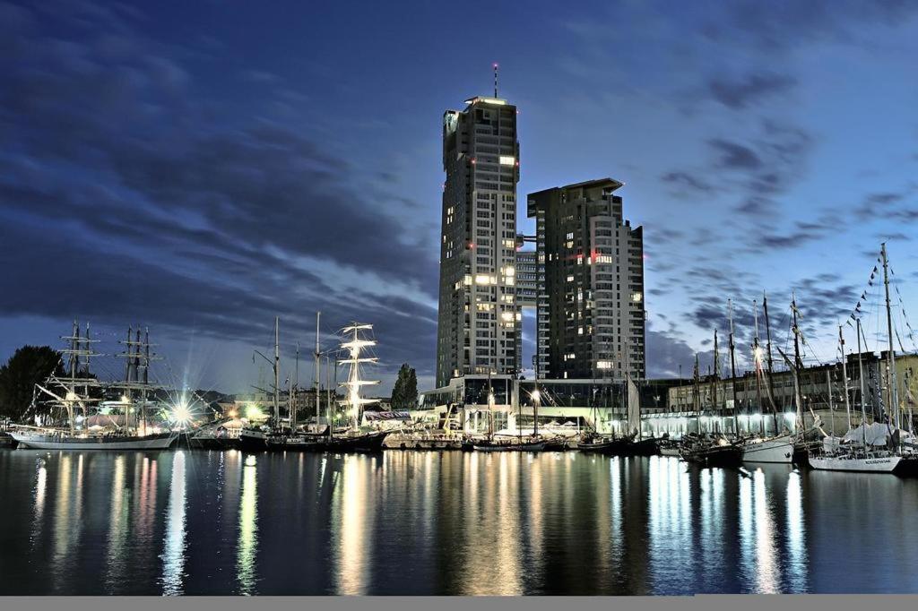 格地尼亞的住宿－Sea Towers Gdynia，夜间码头,有高大的建筑和船只