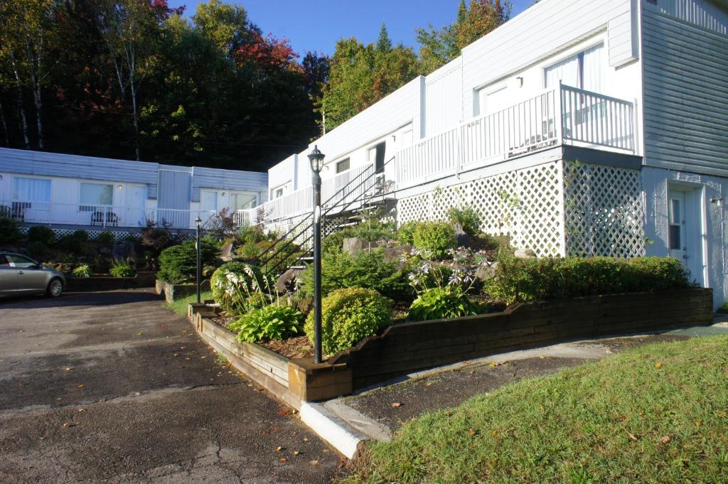 un edificio con un montón de plantas en un patio en Motel Clair Mont, en Sainte-Agathe-des-Monts