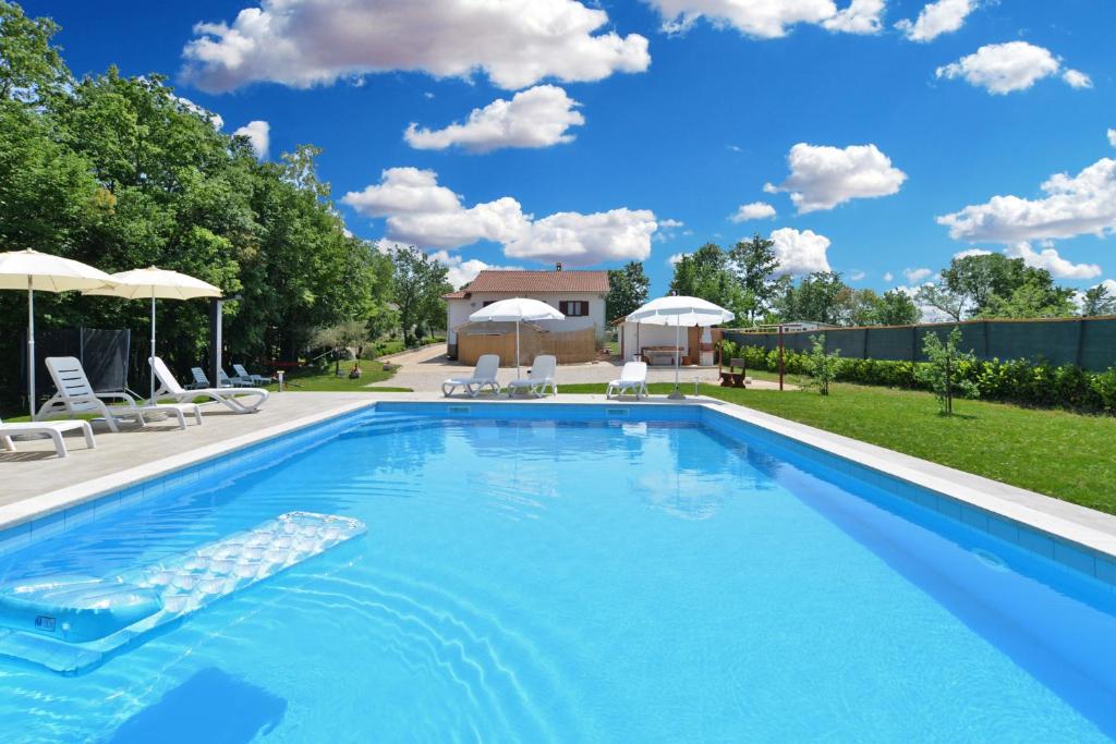 a pool with chairs and umbrellas in a backyard at Apartment Modrusani 1561 in Žminj