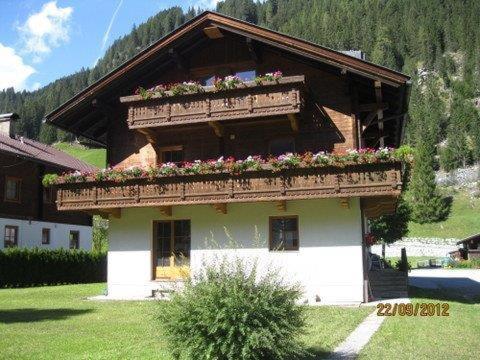 a building with a balcony with flowers on it at Ferienwohnung Artur Wieser in Sankt Jakob in Defereggen