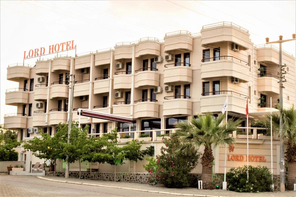 a large white building with trees in front of it at Lord Hotel in Cesme