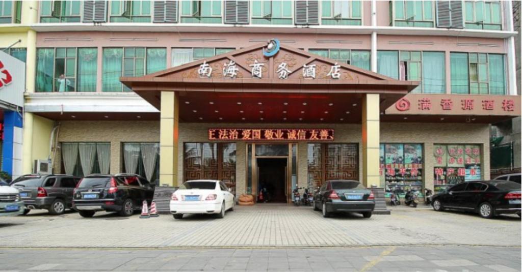 un edificio con auto parcheggiate di fronte di GreenTree Inn Hainan Haikou East Train Station East Fengxiang Road Business Hotel a Haikou
