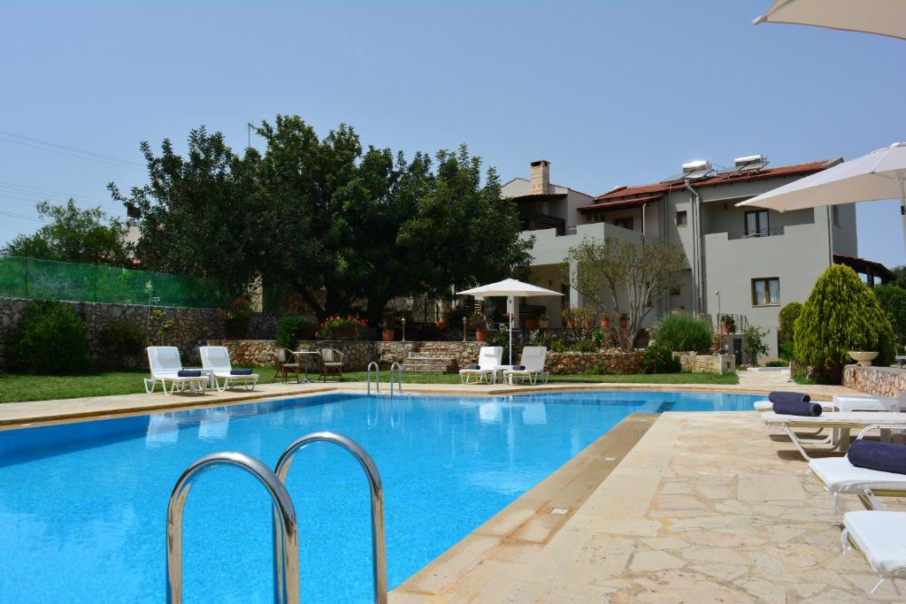 une piscine avec des chaises blanches et un bâtiment dans l'établissement Elianthos Villas, à Vámos
