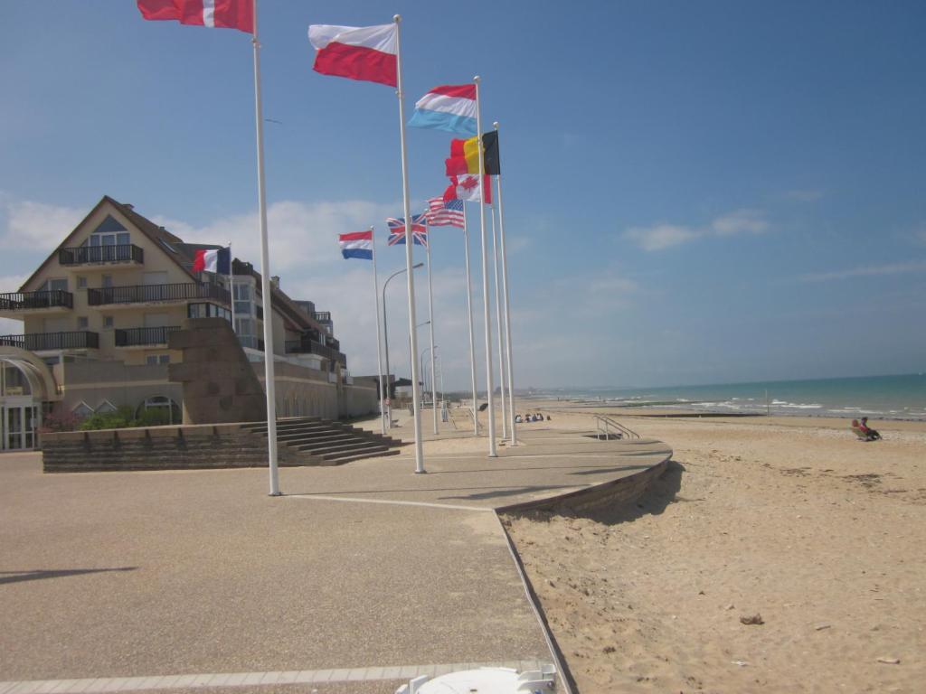 una fila di bandiere su una spiaggia accanto a un edificio di Studio "Voile de nacre" a Bernières-sur-Mer