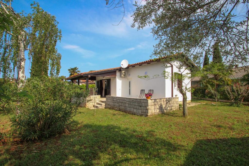 een klein wit huis in een tuin bij Karpinjan in Novigrad Istria