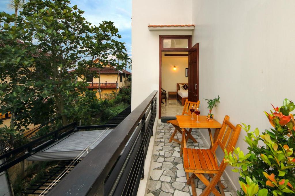 een patio met een houten tafel en stoelen op een balkon bij Hoi An Dat Cam Homestay in Hội An