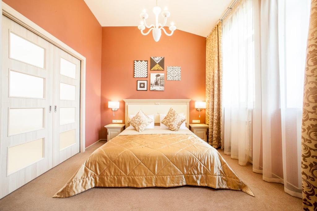 Un dormitorio con una cama con paredes de color naranja y una lámpara de araña. en Mackintosh Hotel en Kiev