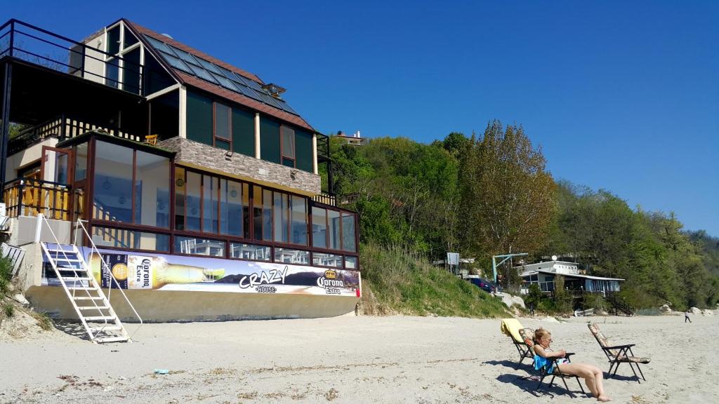 a woman sitting in a chair in front of a house on the beach at Happy beach in Varna City