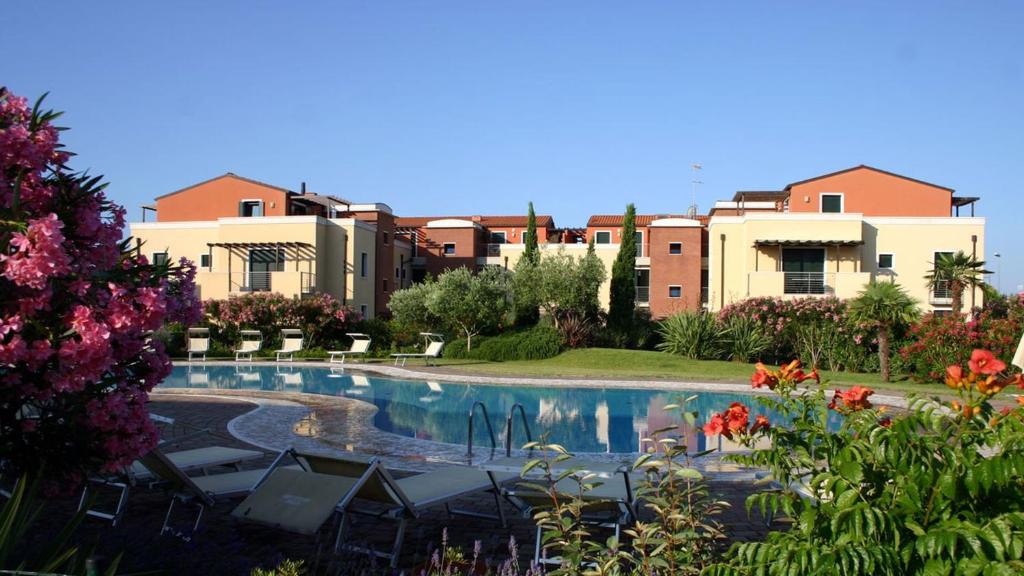 a swimming pool with chairs and buildings in the background at Venezia nature&beach in Cavallino-Treporti