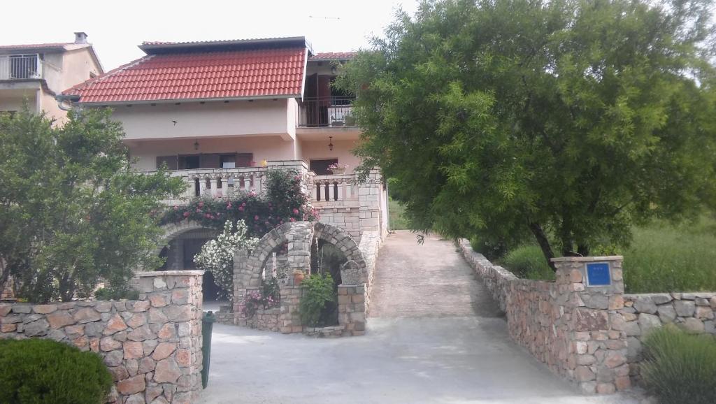 ein Haus mit einer Steinmauer und einem Baum in der Unterkunft Ruža in Skradin