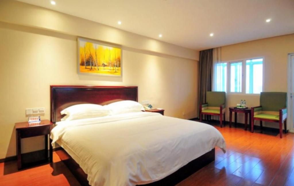a bedroom with a bed and a table and chairs at GreenTree Inn Hainan Haikou Haifu Road Provincial Government Express Hotel in Haikou