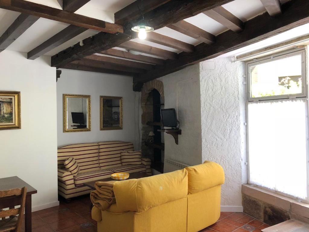 a living room with a yellow couch and a window at Apartamentos La Casona in Ucieda de Arriba