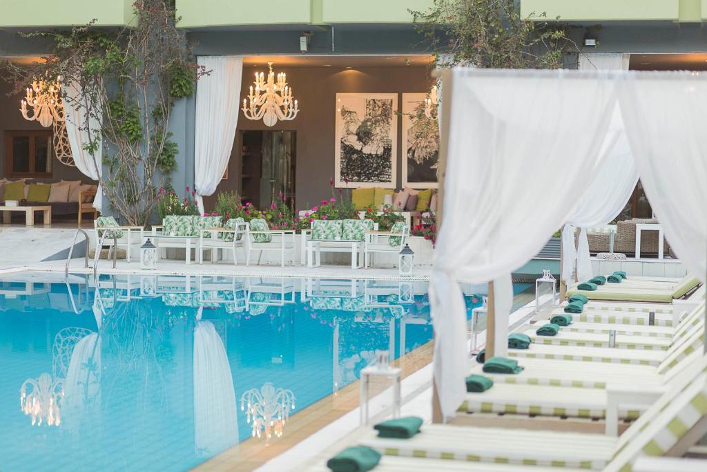 - une table avec des chaises blanches à côté de la piscine dans l'établissement La Piscine Art Hotel, Philian Hotels and Resorts, à Skiathos Chora