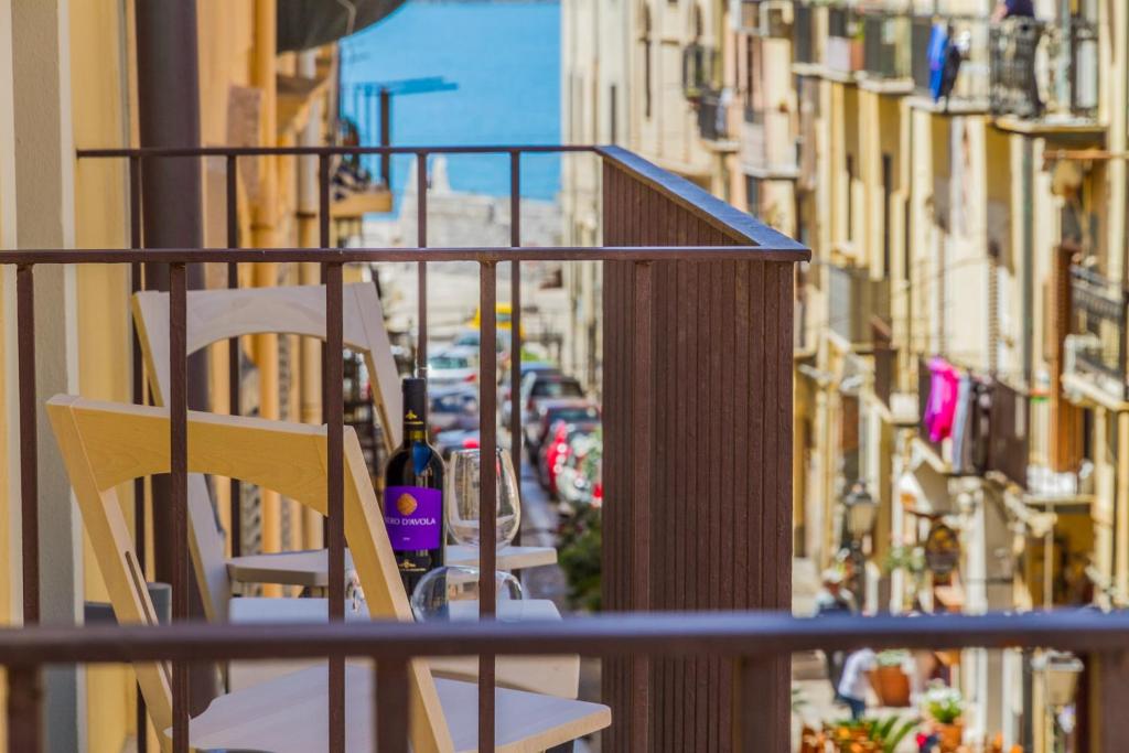 a balcony with a table and chairs on a city street at Suite Bordonaro Apartments in Cefalù