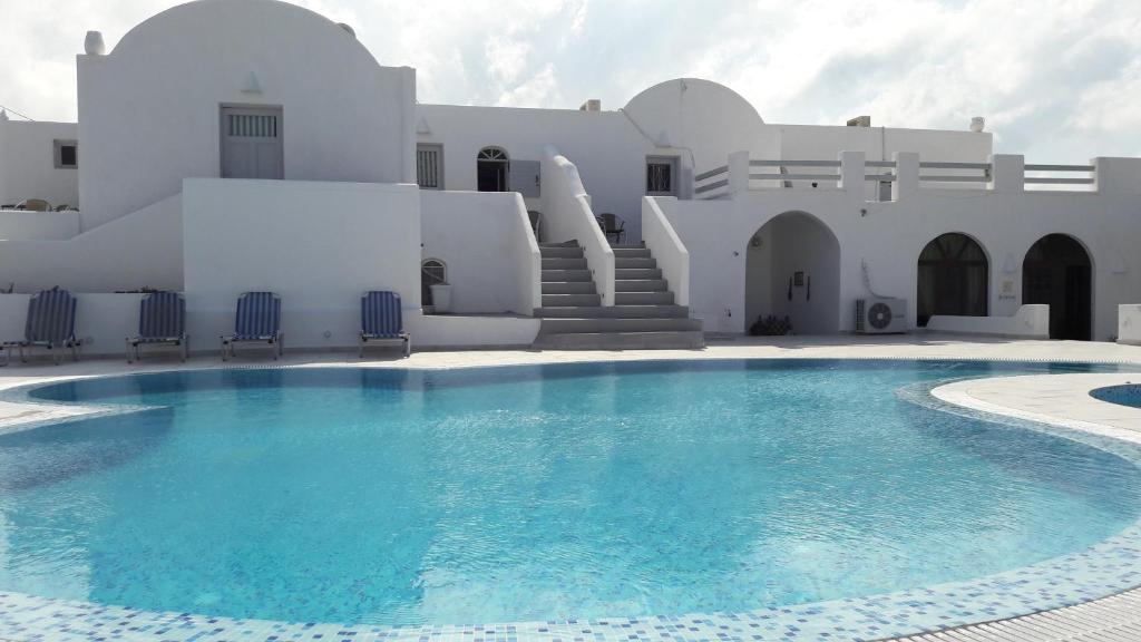 a swimming pool in front of a white building at Villa Iliovasilema Santorini in Akrotiri