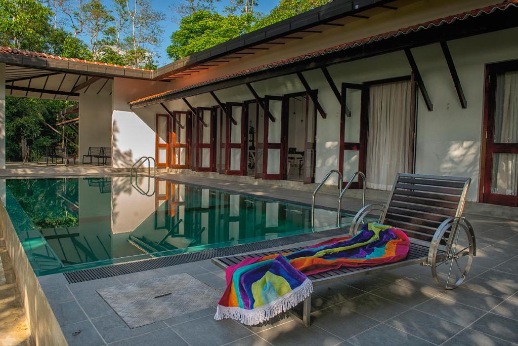 a swimming pool with a bench next to a house at Minnehaha Bentota in Bentota