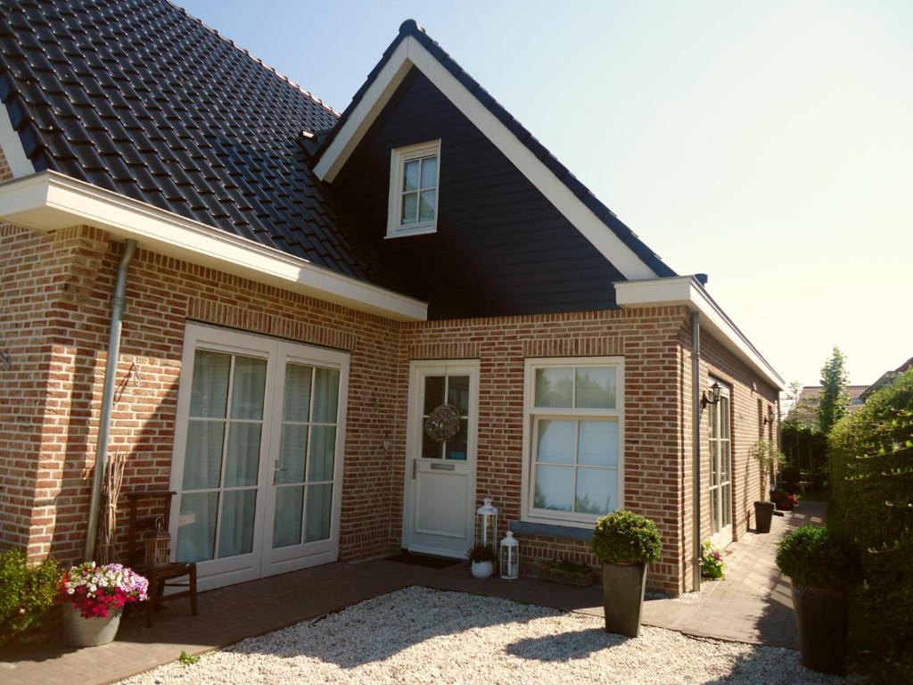 a brick house with a white door at Bed & Breakfast Zeeduinsepoort met Sauna in Oostkapelle