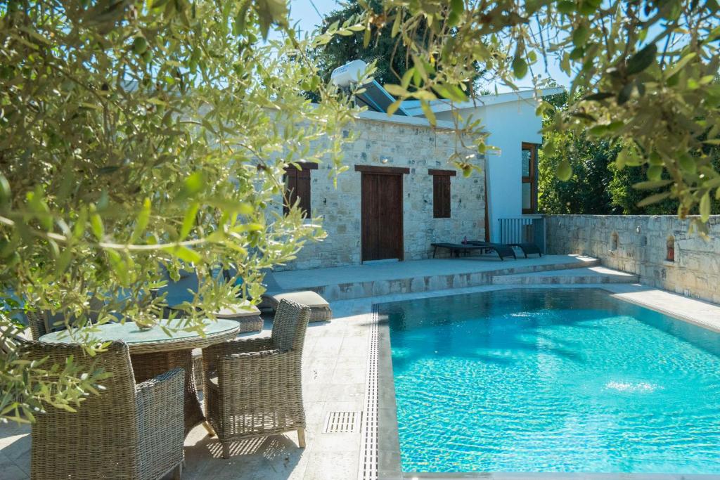 una piscina en un patio con sillas y árboles en Kaizer Agrotourism, en Amargeti