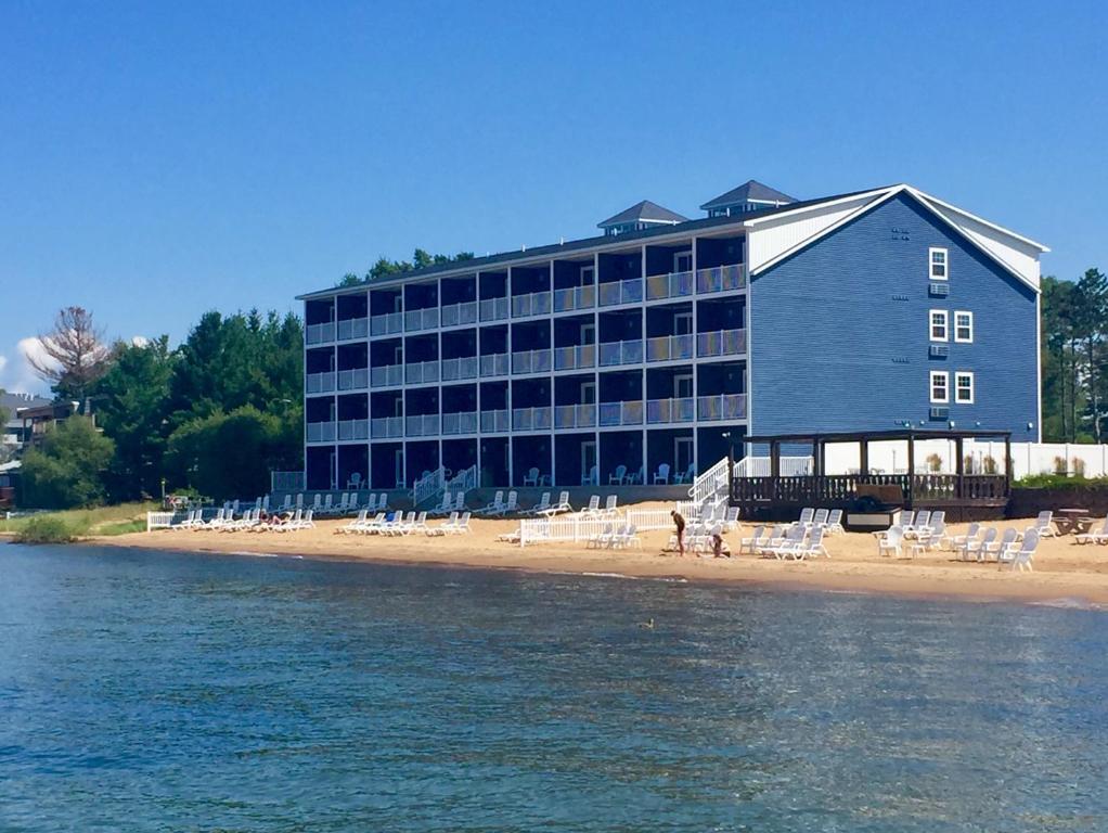 a building on a beach with chairs and the water at The Baywatch Resort in Traverse City