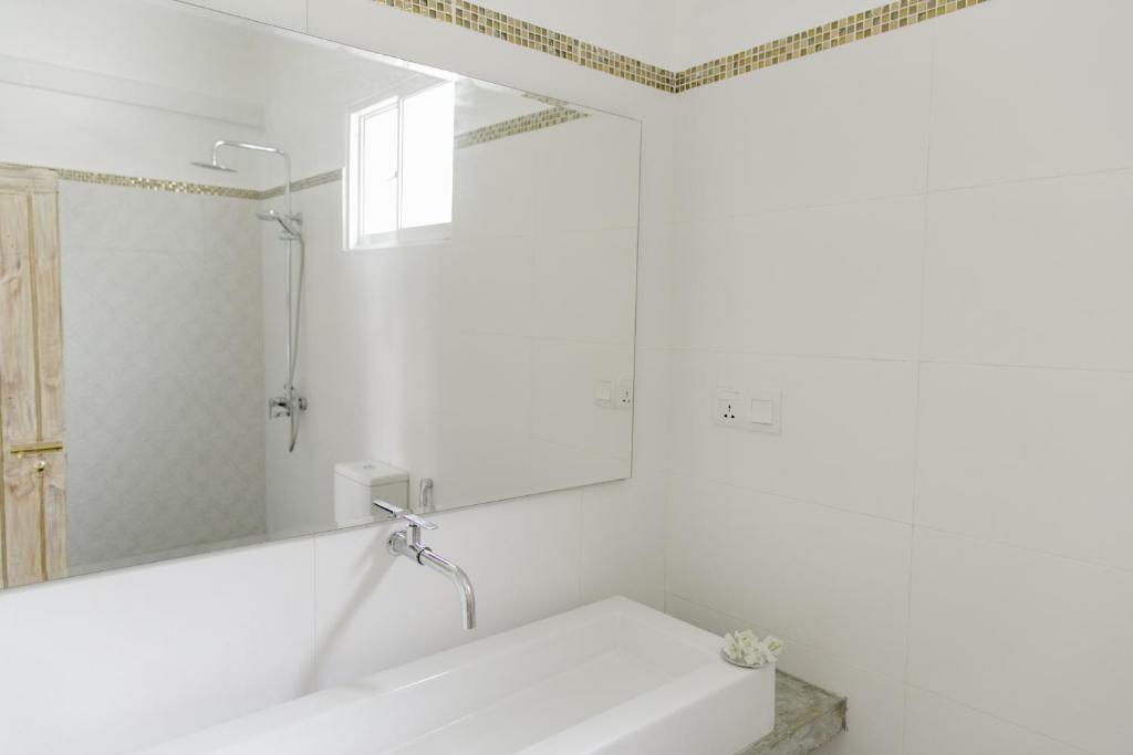 a white bathroom with a tub and a mirror at Nuga Eden Tangalle in Tangalle