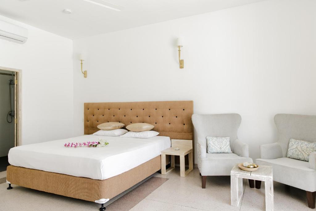 a bedroom with a bed and a couch and a chair at Nuga Eden Tangalle in Tangalle