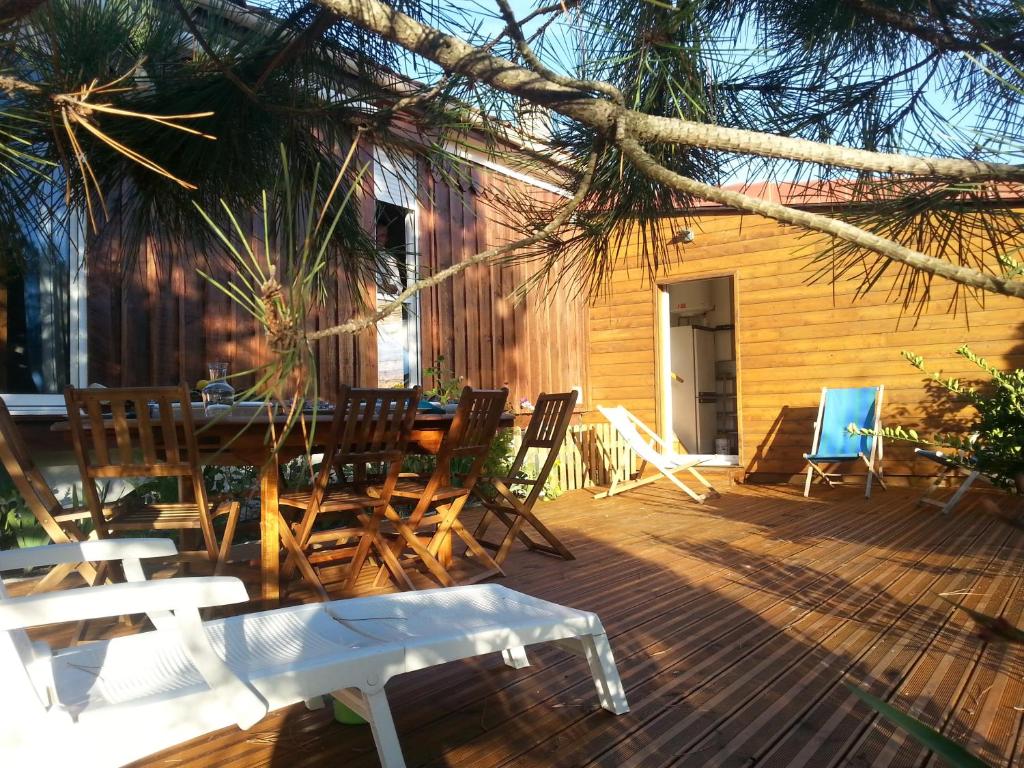 eine Holzterrasse mit einem Tisch und Stühlen darauf in der Unterkunft Villa "Le Mirage" in Cap-Ferret