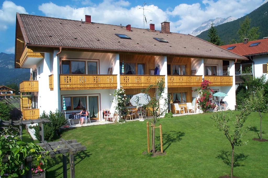 ein großes Gebäude mit Rasen davor in der Unterkunft Ferienapartmenthaus Hubertushof in Mittenwald