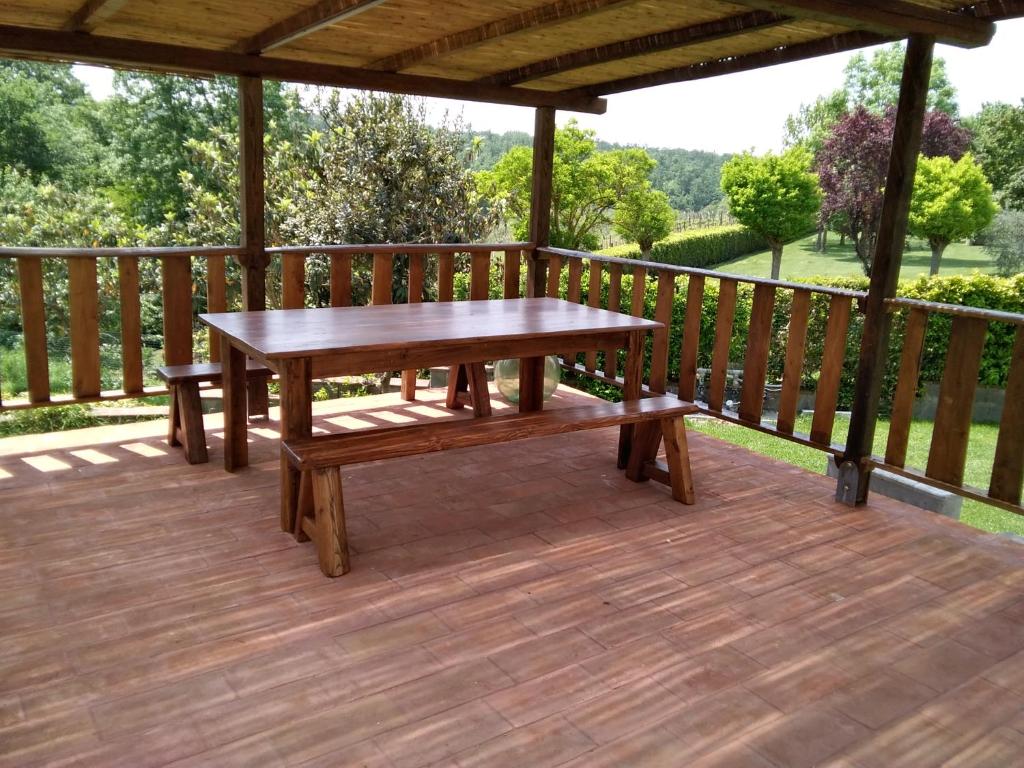una terraza de madera con mesa y bancos. en IL Poggio, en Pontedera