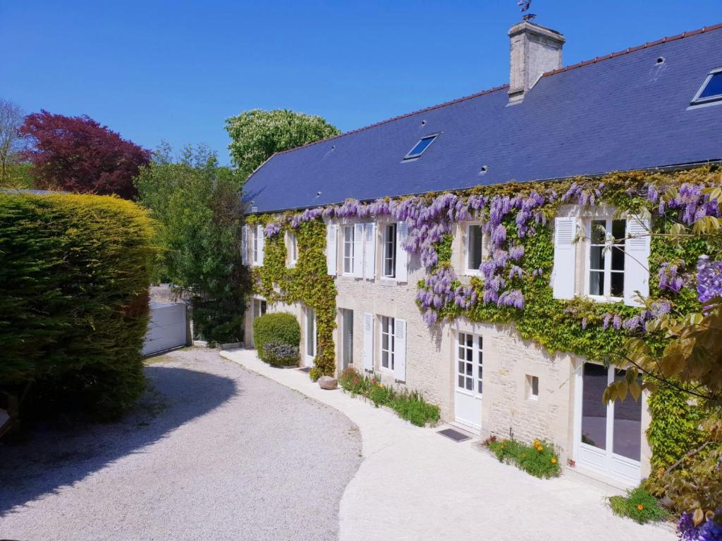 een uitzicht op een huis bedekt met bloemen bij Liz'A logis de Charme in Saint-Côme-de-Fresné