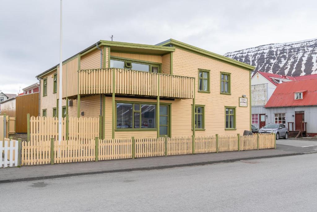 una casa amarilla con una valla delante de ella en Isafjordur Hostel, en Ísafjörður