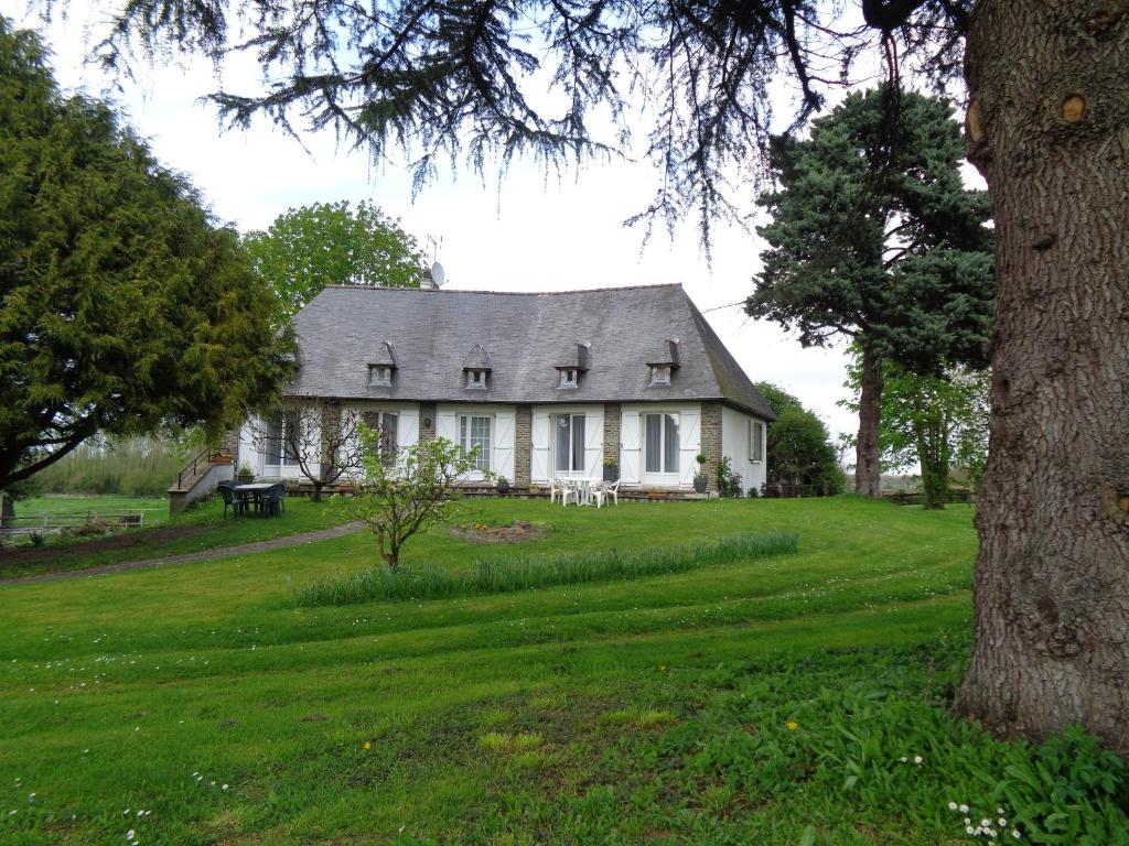 a white house on a green field with a tree at chambre d'hôte in Pontorson