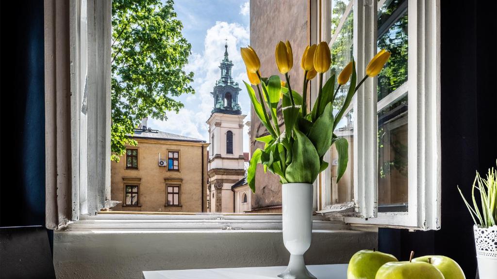 un jarrón blanco con flores amarillas en una ventana en Flaminio Smart Sleep, en Cracovia