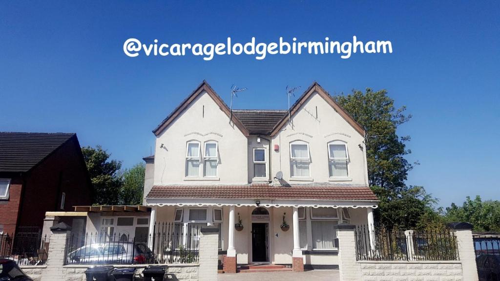 uma casa branca com uma cerca à frente. em Vicarage Lodge Birmingham em Birmingham