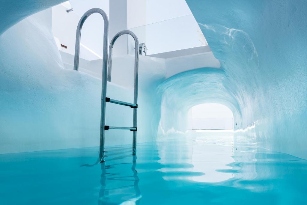 a swimming pool with water in a tunnel at Hyperion Oia Suites in Oia