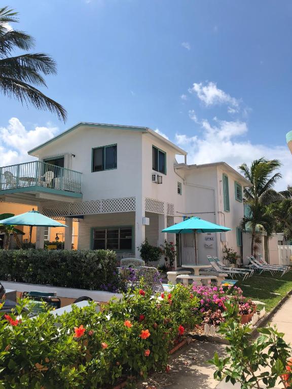 a building with tables and umbrellas in a yard at Atlantic Sands Beach Suites in Hollywood