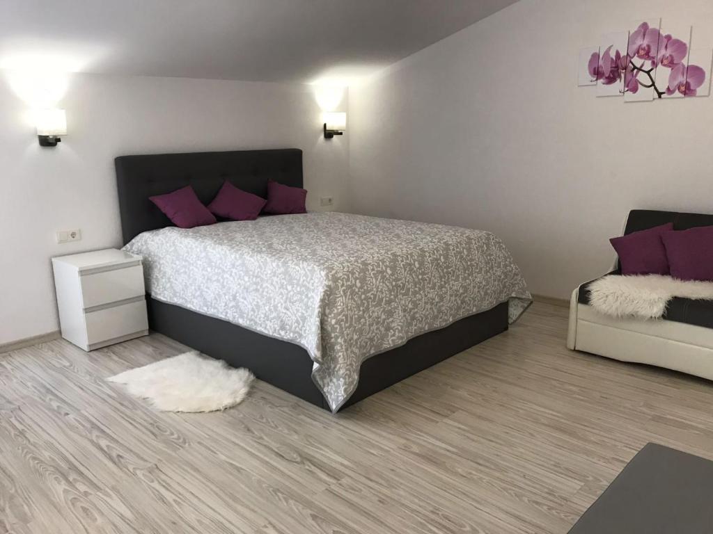 1 dormitorio con 1 cama grande con almohadas moradas en Tukums apartments, en Tukums