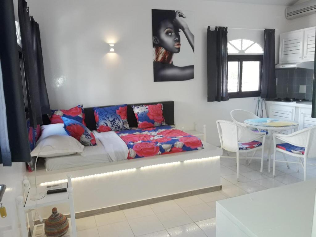 a room with a bed and a table and a kitchen at Studio Lipstick in Saly Portudal