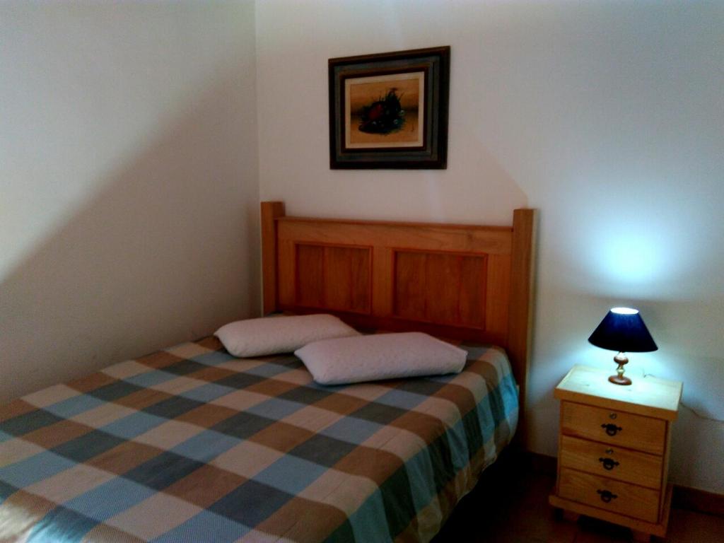 1 dormitorio con cama y mesita de noche con lámpara en Pousada e Chalés Itamoara, en São Thomé das Letras
