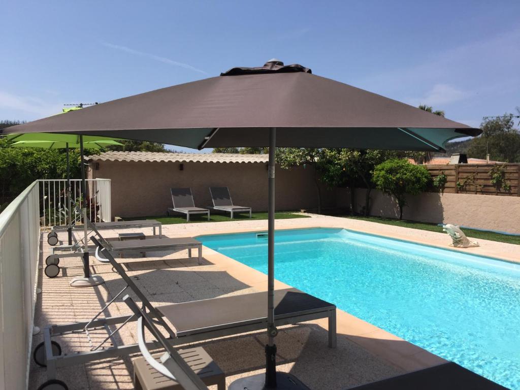 een parasol en stoelen naast een zwembad bij Oustaou di Ercole in Bormes-les-Mimosas