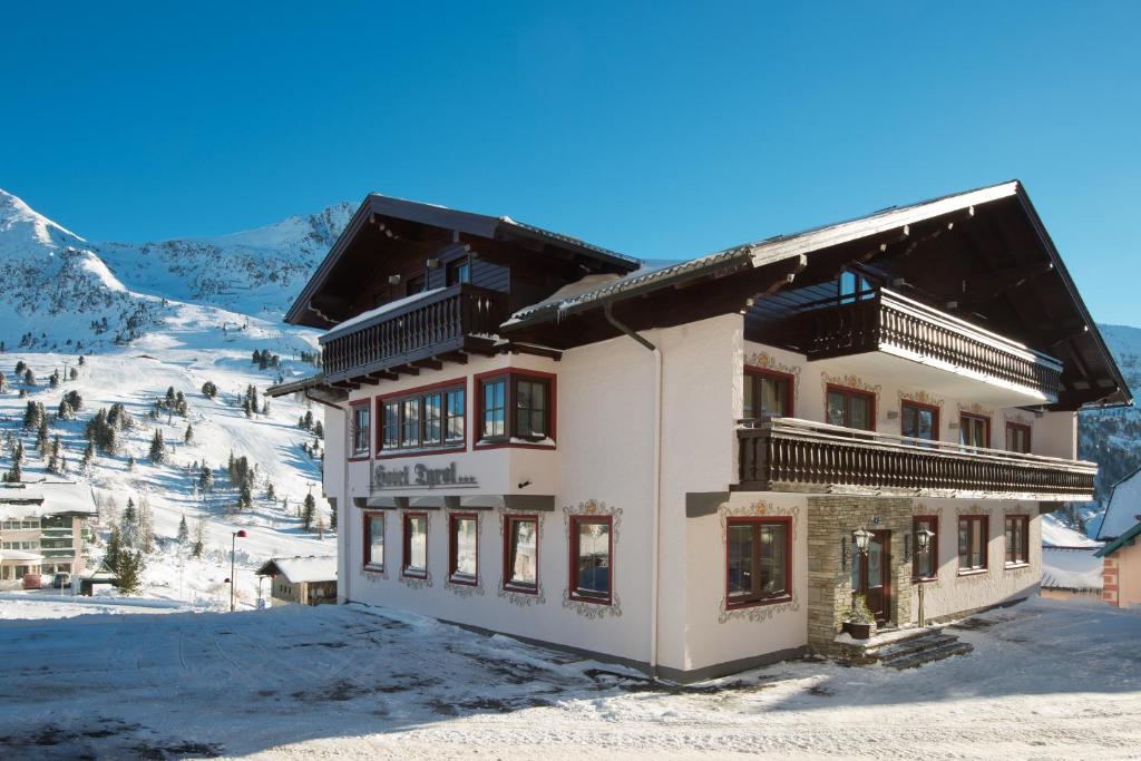 a building in the snow with mountains in the background at Hotel Garni Haus Tyrol in Obertauern
