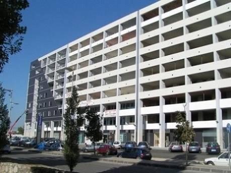 un grand bâtiment blanc avec des voitures garées dans un parking dans l'établissement Uniclub House, à Cosenza