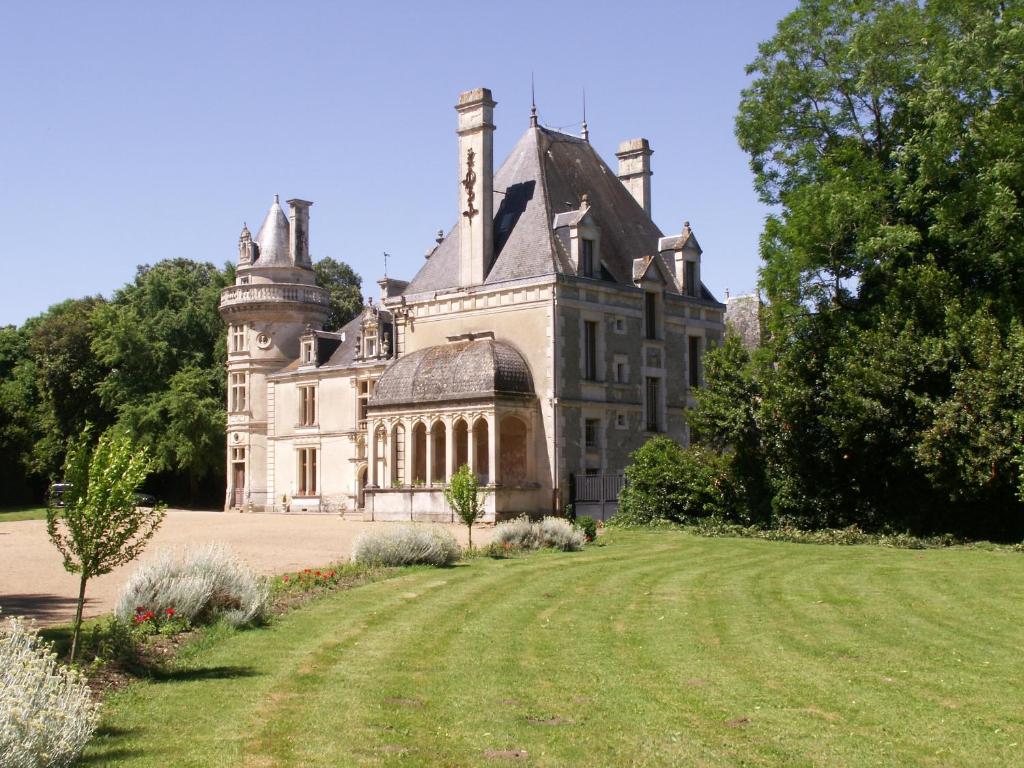 un vieux château avec une pelouse devant lui dans l'établissement Château de la Court d'Aron, à Saint-Cyr-en-Talmondais