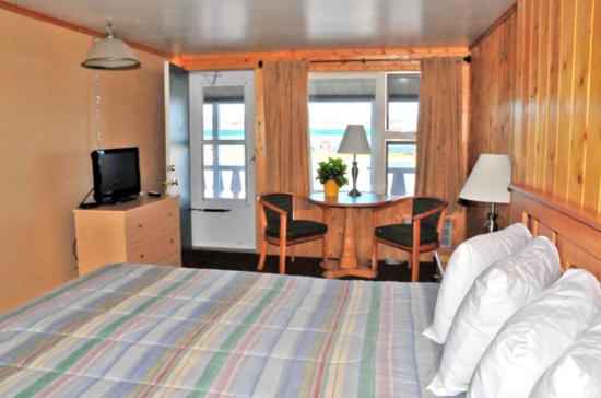 - une chambre avec un lit et une table avec une télévision dans l'établissement The Sunset Motel, à Munising