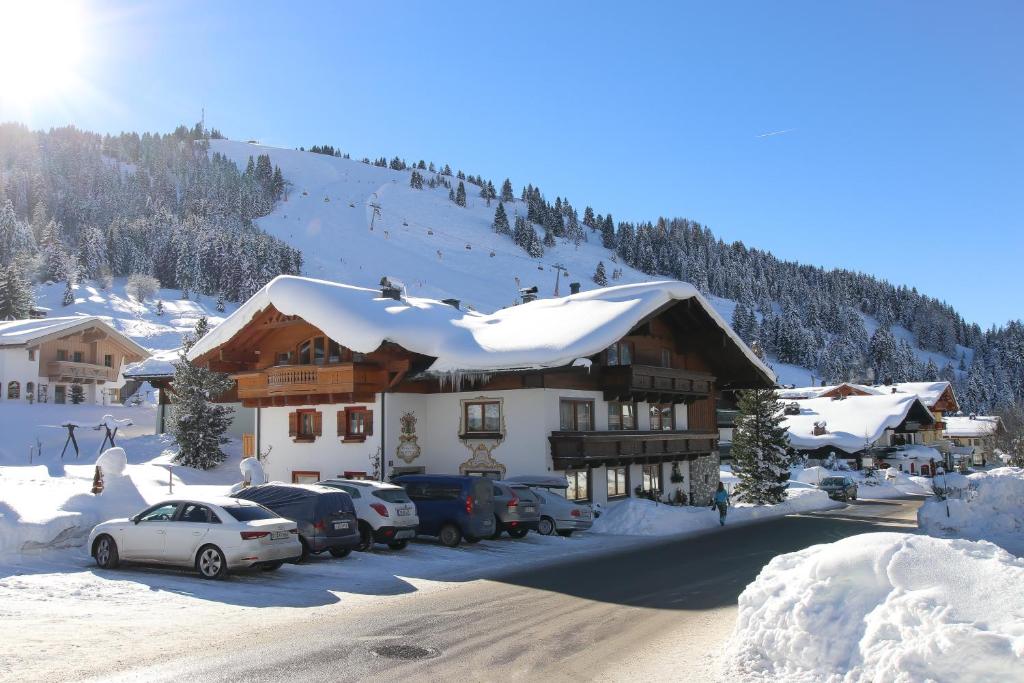 a snow covered building with cars parked in front of it at Haus Bergliebe in Maria Alm am Steinernen Meer
