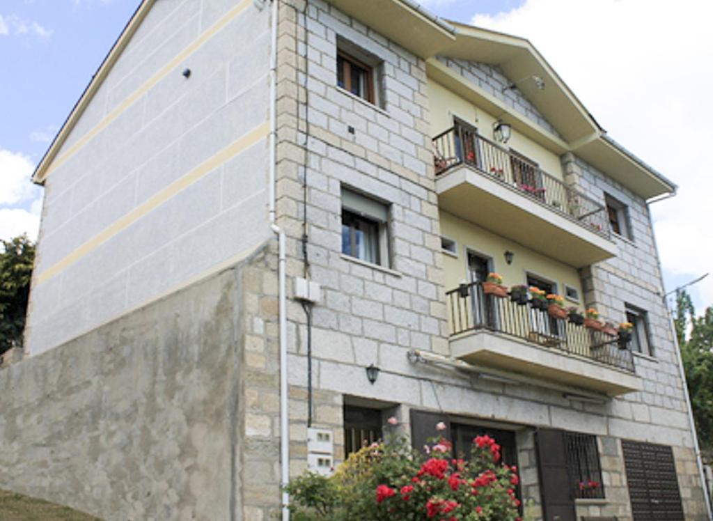 ein Gebäude mit zwei Balkonen und Blumen davor in der Unterkunft Apartamentos Monasterio in San Martín de Castañeda